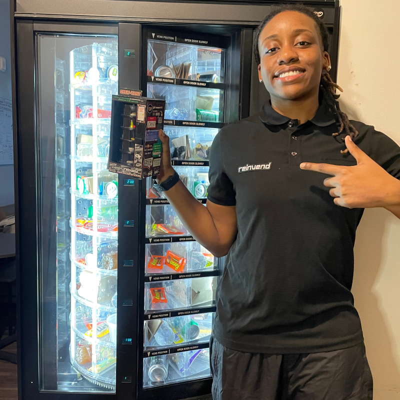 Co-founder Kiandra Peart poses with a prototype of Reinvend in front of a campus vending machine.